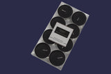 Set of eight black candles in a clear plastic packaging on a white background